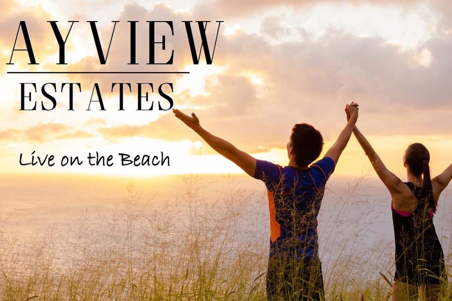 Two people on the beach with arms outstretched looking at the sunset.